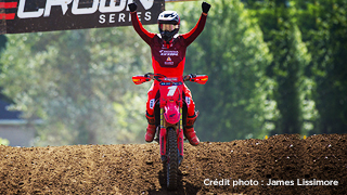 Un coureur Honda sur son vélo sur une piste, levant les bras dans la victoire. Crédit photo à James Lissimore.