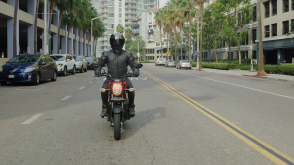  A rider riding a Honda Navi down a city street, front facing