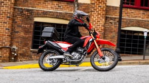 A side angle view of a person riding the Honda CRF300L on a city street