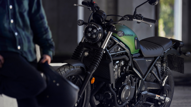 a rider holding a helmet and a Honda motorcycle/un cavalier et un motocyclette Honda
