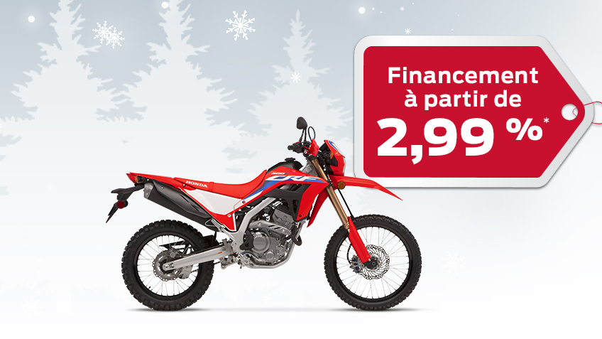Une Honda CRF300L sur un dos d'hiver avec des flocons de neige avec une étiquette de cadeau rouge annonçant un taux d'intérêt de 2,99%